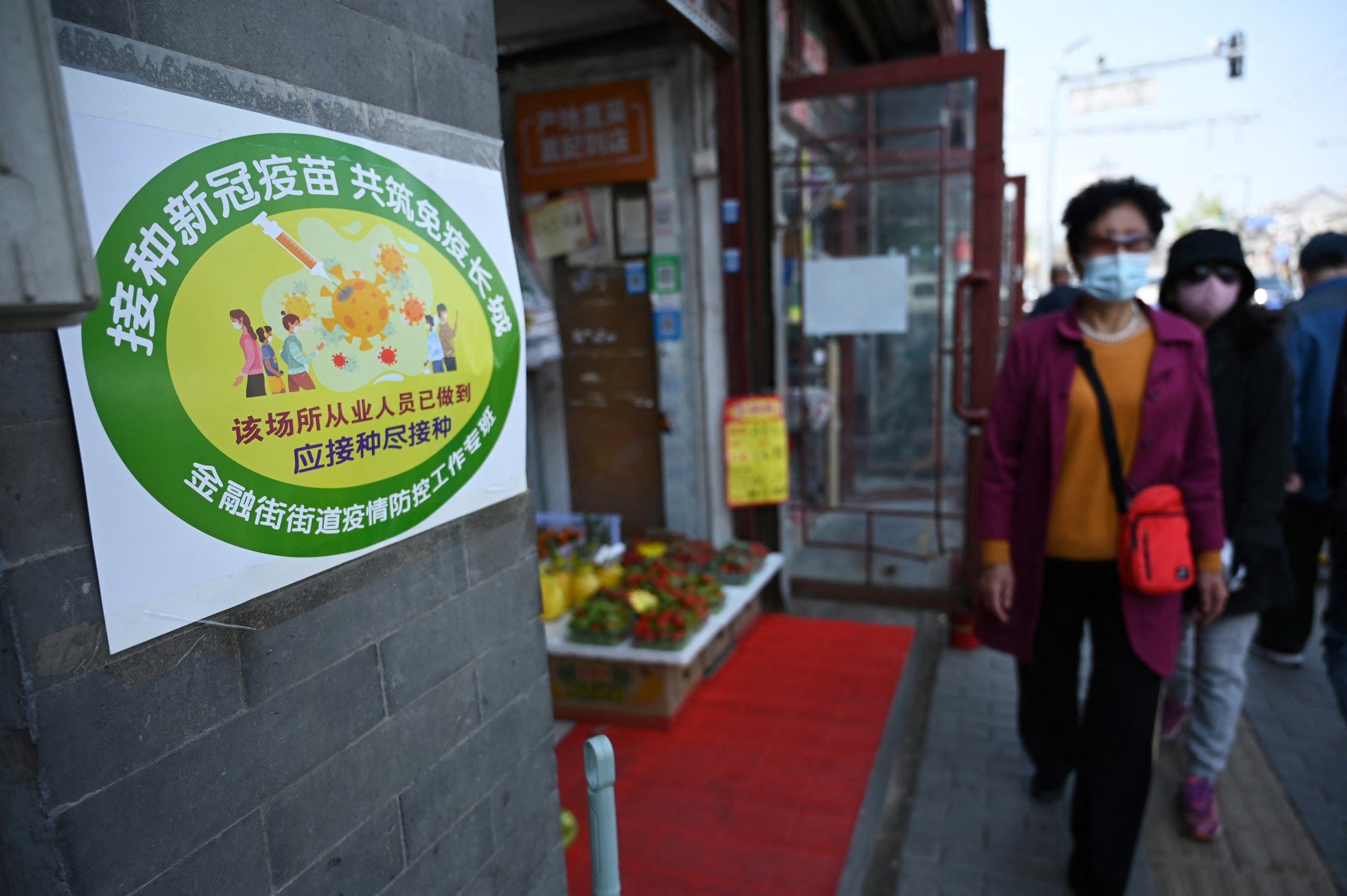علامة خضراء على باب متجر خضار في بكين تشير إلى أن معظم العاملين فيه تلقوا اللقاح