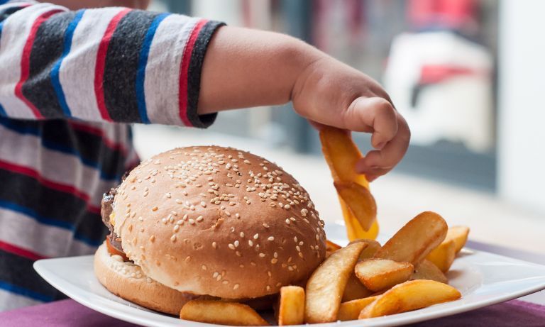 kid-grabbing-french-fry-from-hamburger-plate-768