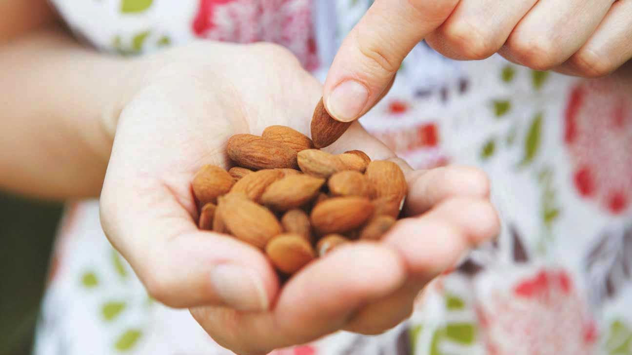 woman-holding-almonds-in-palm-of-hand-1296x728-1